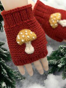 Knitted mushroom-themed fingerless gloves styled with autumn leaves and natural woodland elements."